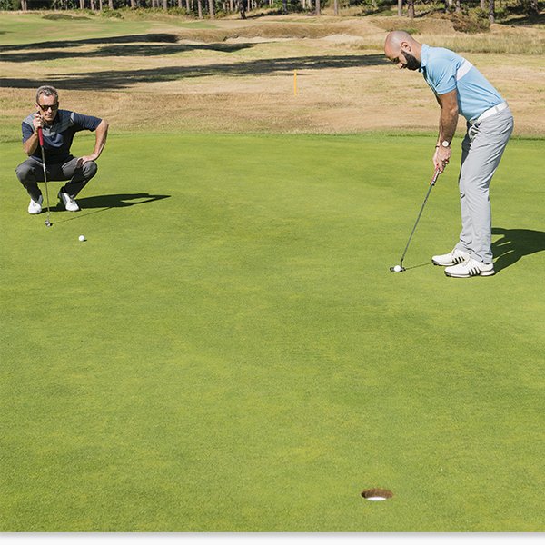 Golfer Lining Up a Putt During Playing Partner's Putt